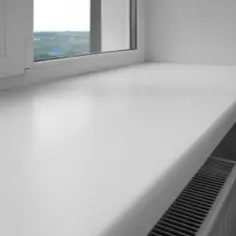 Biały, szeroki parapet okienny z tworzywa sztucznego, pod którym widać grzejnik. Czy parapet jest konieczny? To pytanie zadaje sobie wielu, ale ten dodaje funkcjonalności.