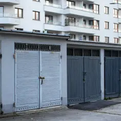 Rząd garaży z szarymi, drewnianymi i metalowymi wrotami. Zastanawiasz się, ile kosztuje wymurowanie garażu?