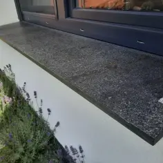 Granitowy parapet zewnętrzny, idealnie dopasowany do okna, stanowi przykład, jak prawidłowo zamontować parapet zewnętrzny.