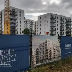 Budowa osiedla mieszkaniowego w Gdańsku z żurawiem i banerami deweloperów.