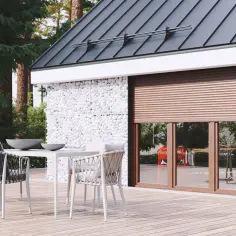 Nowoczesne okna z roletami w brązowej ramie, otoczone kamiennymi gabionami, tworzą stylową fasadę domu.