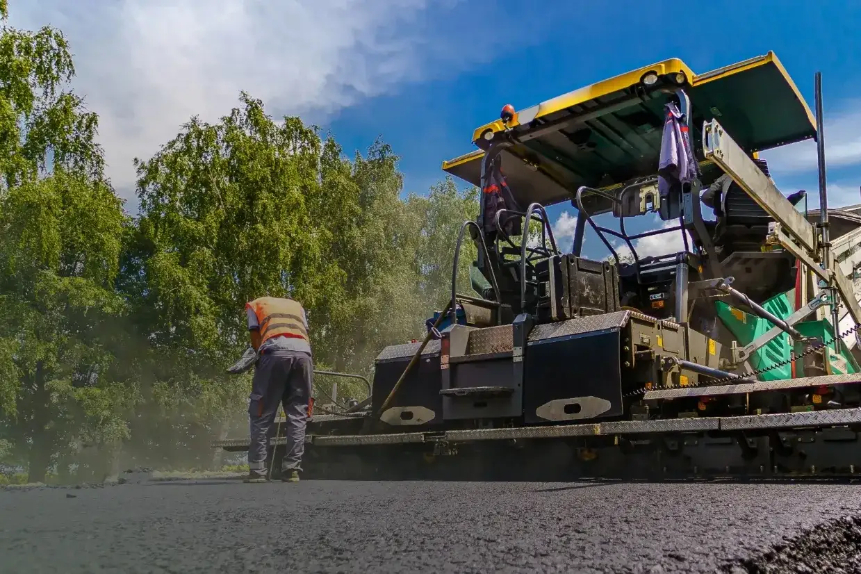 Robot drogowy układa asfalt. Zastanawiasz się, ile kosztuje zrobienie drogi dojazdowej?