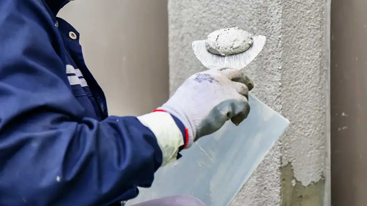 Pracownik nakłada tynk na elewację. Dowiedz się, ile kosztuje położenie struktury na elewacji.