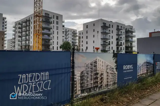 Budowa osiedla mieszkaniowego w Gdańsku z żurawiem i banerami deweloperów.